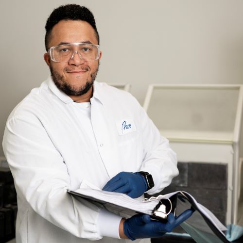 Scientist in lab coat and safety glasses hold open binder